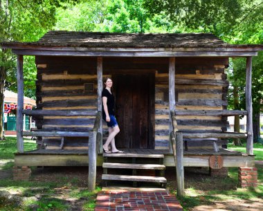 Kütük kulübesi Collierville, Tennessee meydanında. Kulübe 1800 'lerin ortalarında posta arabası durağı olarak kullanılmış. Çekici genç kadın merdivenlerde duruyor..