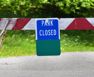 Park alanına giden bariyerleri kapatın. Eyalet parkı COVID 19 virüsü yüzünden kapalı. Bariyer kırmızı beyaz çizgili ve mavi işaretli..
