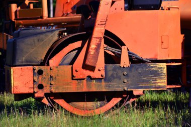 Yol geliştirme ve inşaatlarda kullanılan bu otoyol ekipmanında parlak turuncu boya kaba ve kırsaldır. Resim tekerleği gösterir.