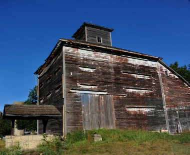 Su kuyusu alışılmadık bir ahır yapısının önünde duruyor. Yıpranmış ahşap beyazdan körelmiş griye dönüşmüş. Üzerinde bir kubbe olan ahır Kansas 'ın merkezinde yer alır..