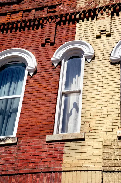 stock image Old red and yellow brick building has narrow windows.  Decorative wooden arches over windows are white.  Building sits in Counciil Grove, Kansas.