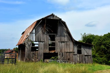 Terk edilmiş ahşap ahır, kayıp tahtalar, paslı teneke çatı ve kırık kapılar ile yıkıldı..