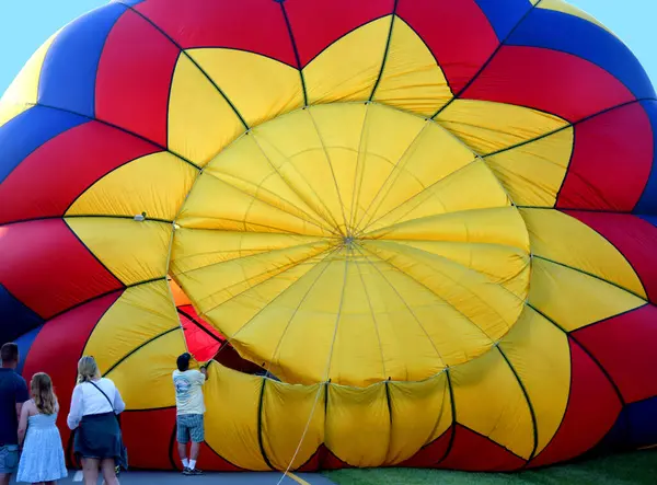 Sıcak Hava Balonu, Kingsport, Tennessee 'deki Hot Air Balon Festivali sırasında uçuşuna hazırlanırken genişler ve şişer. Seyirciler, işçiler hazırlarken izliyorlar..