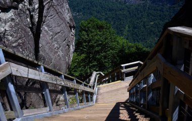 Steep steps ascend to the top of Chimney Rock, Chimney Rock State Park, North Carolina.  Stairs are wooden with metal and wood rails.  Rock bluff is besides. clipart