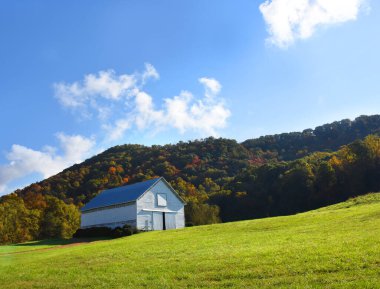 Tennessee 'nin Appalachian Dağları' ndaki beyaz, yıpranmış ahşap bir ahırın önünde güneş parlıyor. Apalaş 'lılara sonbahar geldi..