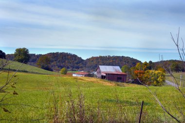 Appalachian dağ çiftliği sonbahar dağlarını görüyor. Çiftlik dışında yollar da var. Ahır teneke çatıyla kırmızıdır..