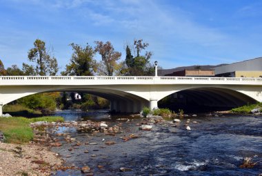 Elk Street Arch Bridge crosses the Doe River in Downtown, Elizabethton, Tennessee.  Bridge is painted white and is concrete.  Sky is blue. clipart