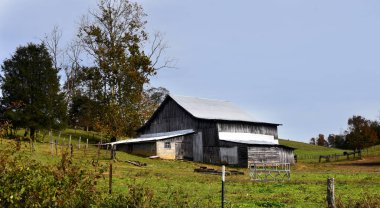 Tennessee 'nin Appalachian Dağları' ndaki bir yamaçta, yıpranmış ahşap bir ahır var. Çatı teneke..