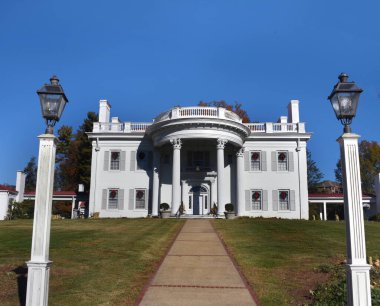 Grand and beautiful, Allendale Mansion stands against a blue sky.  Classic Georgian architecture, has Christmas wreaths decorating windows. clipart