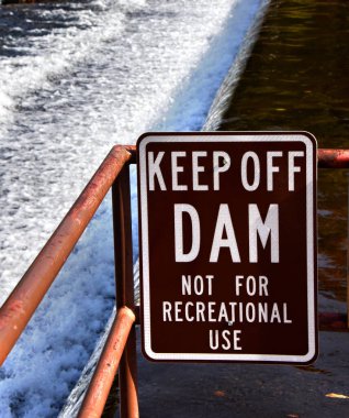 Beyaz harfli kahverengi tabela, ziyaretçileri barajdan uzak durmaları konusunda uyarıyor. Spillway arka planda görülebilir. Baraj, Tennessee Elizabethon 'daki Doe Nehri' ni kontrol ediyor..