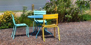 Sarı ve turkuaz metal yemek seti Memphis, Tennessee 'deki Mississippi nehri kıyısındaki River Garden' da bulunur. Masanın yanında çiçekler açar..