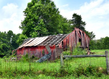 Hava durumu, solmuş ve harap olmuş, kırmızı ahır çitlerle çevrili. Çatı neredeyse tamamen çökmüş ve tahtalar yamulmuş ve kırılmış..