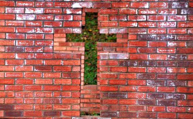 Brick architecture has cross shaped opening.  Behind front opening is another cross shaped opening.  Brick is red. clipart