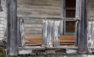 Eski bir evin kalıntıları ön verandanın kırıldığını ve çürüdüğünü gösteriyor. Veranda korkuluğundaki tahta levhalar kayıp. Yeni tahtalar korkulukların arkasında unutuldu.