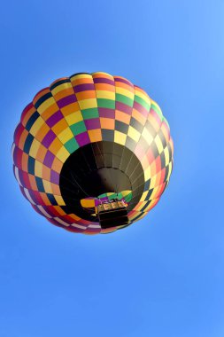 Colorful, geometric design, hot air balloon rises above Collierville, Tennessee.  Blue skies great balloon during hot air balloon festival. clipart