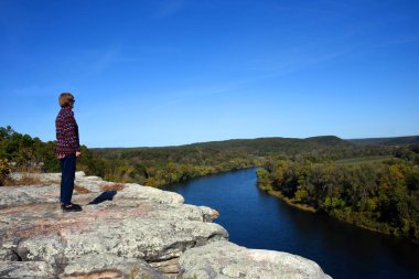 Kadın Arkansas, Calico Rock 'taki City Bluff Overlook' un kenarında duruyor. Tekne, aşağıdaki Beyaz Nehir 'in kıvrımlarında kaybolur..