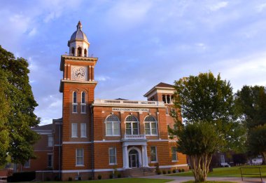 Sabah güneşi Arkansas 'ın Bradley County Adliyesi' nin saat kulesini aydınlatıyor. Bina bronzlaşmış ve turuncu tuğlalı, tepesinde polis kubbesi var.. 