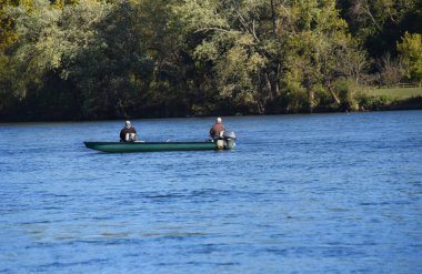 İki adam Arkansas 'taki Boswell Shoals' da, Beyaz Nehir 'in sakin sularında balık tutuyor. Tekne turkuazdır..
