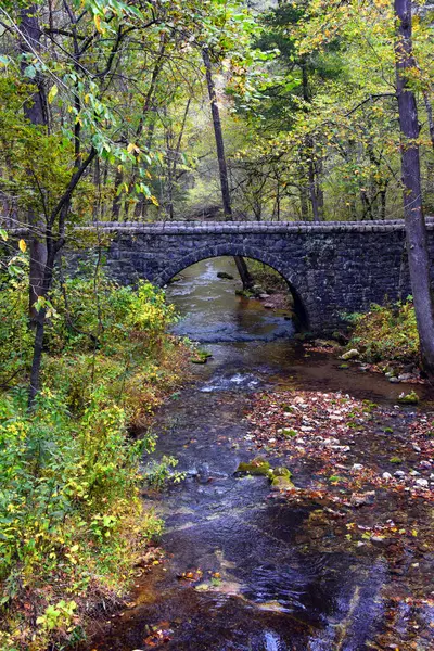 stock image Tranquil scene within the Blanchard Springs Caverns recreation area shows half-moon, stone bridge.  North Sylamore Creek flows gently beneath stone arch.