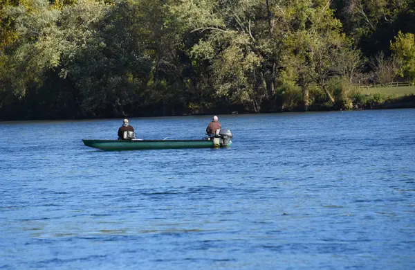 İki adam Arkansas 'taki Boswell Shoals' da, Beyaz Nehir 'in sakin sularında balık tutuyor. Tekne turkuazdır..