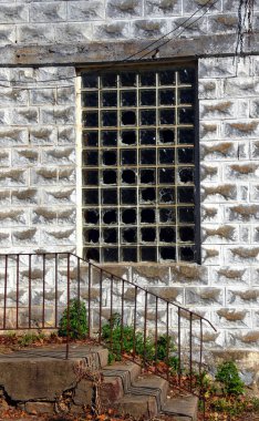 Arkansas, Calico Rock 'taki Pepper Sauce Alley' de terk edilmiş cenaze evinin önünde paslı demir parmaklıklar ve beton merdivenler var. Çoklu camlı camlar kırılmış..