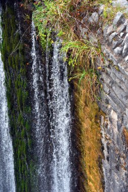 Arkaplan resmi Ayna Gölü Barajı ve Şelalesi 'nin taştan duvarındaki desenleri gösteriyor..