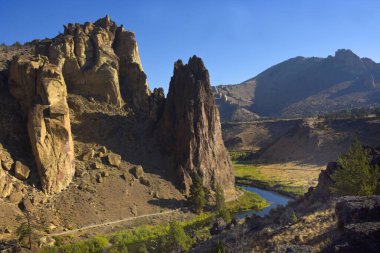 Güzel mavi gökyüzü Oregon 'daki Smith Rock State Parkı' nın üzerinde asılı. Eğri Nehir gökyüzünü yansıtır. Dağın eteklerinde rüzgarlar esiyor..