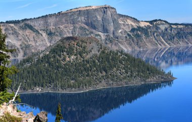 Büyücü Adası, kül konisi, hep yeşilliklerle kaplıdır. Ada, Oregon 'daki Krater Gölü Ulusal Parkı' ndaki Krater Gölü 'nün sakin ve mavi sularına yansıyor..