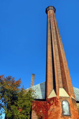 Calumet and Hecla County Copper Mine shaft is framed by vivid blue sky.  Brick shaft has hinged door for easy ash removal during the mining process. clipart