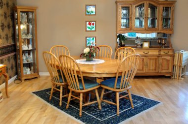 Şehir tarzı yemek odasında oval, meşe masa ve altı sandalye var. Antika dolabı ve porselen dolap desenli halı ve ahşap kaplamalı duvarlar.