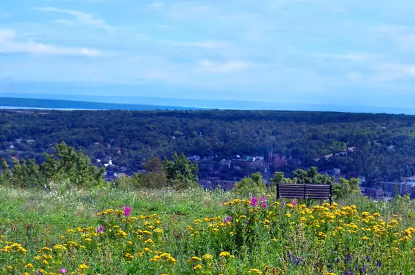 stock image Park bench sits on top of Quincy Hill overlooking the town of Houghton, Michigan.  Sweeping vista includes Lake Superior.