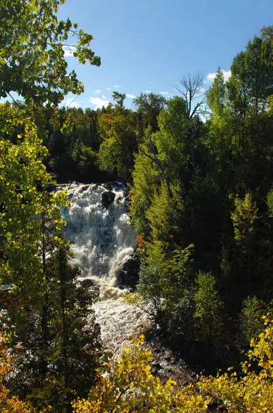 stock image Eagle River spills over rocky ledge at Eagle River Falls in Upper Peninsula, Michigan.  Fall colors foreground.