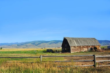 Mutluluk Vadisi, Montana 'da bir tarlada bulunan Rustik, direkli bir ahır. Tahta çitler mercanı tetikliyor. Çatı ahşap..