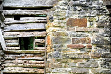 Background image shows wall of the historic Villines Cabin in the historic area of Boxley Valley in Arkansas.  Cabin has hand hewn logs and stone chimney. clipart