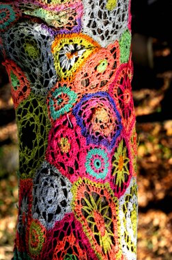 Park in Eureka, Springs has decorated tree trunks with old crocheted afghans recycling them.  This pattern has flowers in multiple colors. clipart