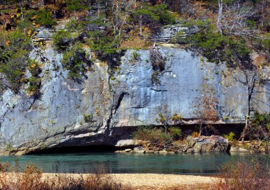 Rugged granite cliffs overhang aqua blue water on the Buffalo National River outside of Harrison, Arkansas. clipart