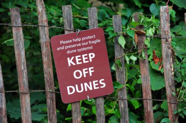 Indiana 'daki Indiana Dunes Ulusal Parkı' ndaki kum tepelerinin yakınlarına tabela asılmış. İşaret kırsal bir çite iliştirilmiş..