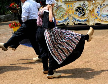 Genç çiftler, kostümlü, geleneksel bir Hollanda dansı yapıyorlar. Ahşap ayakkabı giyiyorlar..