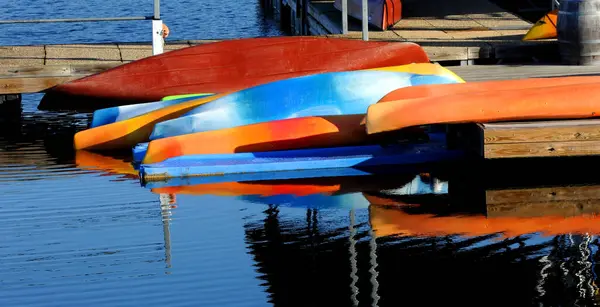 stock image Vivid and colorful canoes lay upside down at the marina at Table Rock State Park in Branson, Missouri.  Beautiful reflection is mirrored in the calm water.