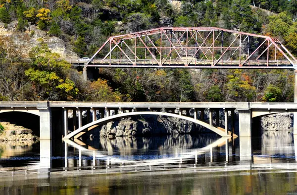 stock image Two bridges cross Bull Shoals Lake.  One is a older steel bridge and the other a concrete structure.  Bottom bridge is reflected in the water.