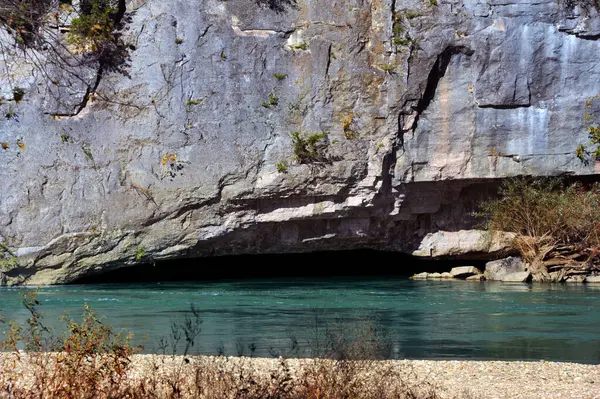 stock image Shallow overhang is part of cliff that towrs over the Buffalo National River near Harrison, Arkansas.  Water is aqua blue.