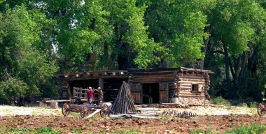 Santa Fe, New Mexico 'nun dışındaki El Rancho De Las Golandrinas' da bir vagonun önünde iki canlandırmacı duruyor..  