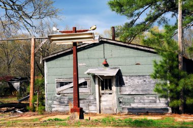 Terk edilmiş bir köy mağazası, pencereleri tahtalarla kaplanmış ve paslanmış levhalarla oturuyor..  