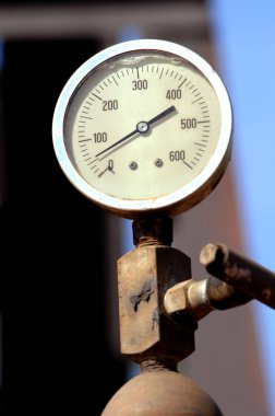 Gauge measures the PSI on an oil derrick.  It is weathered and rusty and measures a little over 50. clipart