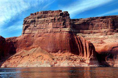 Arizona 'daki Powell Gölü kıyıları boyunca uzanan kırmızı kumtaşı kayalığı mavi gökyüzüne uzanır..