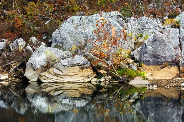 stock image Layered rock sits on the Buffalo River shoreline.  It is mirrored in the still waters, and surrounded by Fall foliage.