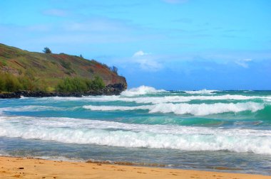 Hawaii, Kauai Adası 'nda ıssız bir sahil kayalık ve kumlu bir plaj var. Su ve gökyüzü mavi.