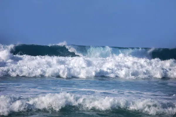 Büyük turkuaz dalgalar Hawaii 'deki Kauai adasına doğru iniyor, yuvarlanıyor ve çarpışıyor..