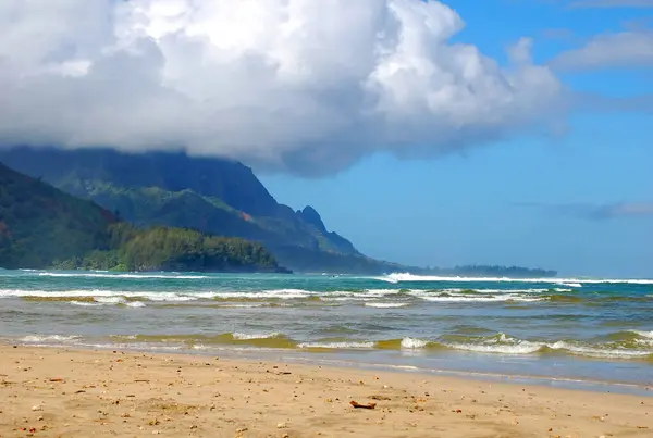 Hanalei Körfezi, Kauai, Hawaii 'deki dağları çevreleyen turkuaz sular. Bulutlar genişliyor ve dağın tepelerini kaplıyor..