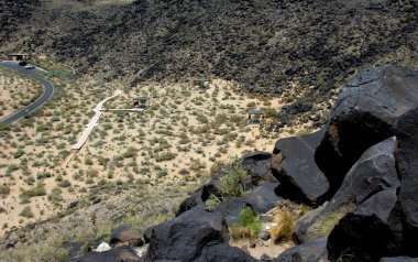 Dik yürüyüş, New Mexico, Alburquerque dışındaki Petroglyph Ulusal Anıtı 'ndaki petrogliflere götürür. Bazalt kayadaki petroglyph sağ tarafta görülebilir..